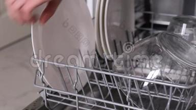 女人把白色<strong>脏盘子</strong>放进洗碗机篮子和特写手